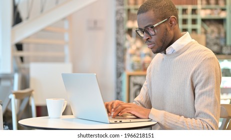 Focused African Man Working on Laptop in Cafe - Shutterstock ID 1966218151