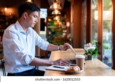 Focused Asian College Student Shut Down His Laptop In Cafe.