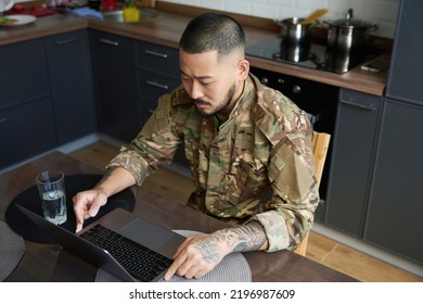 Focused Asian Soldier In Camouflage Uniform, Sitting In Front Of Laptop