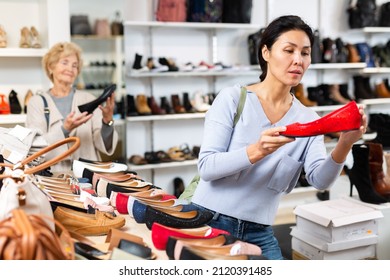 Focused Asian Woman Who Came To A Shoe Store For Shopping, Chooses Ballet Flats, Carefully Examining Them