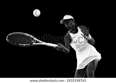 Focused athlete in poised stance ready for backhand return in tennis against black studio background. Monochrome filter. Concept of women in sport, active lifestyles, energy, movement.