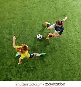 Focused athletic women in their early 20s, in mid-action on soccer field, both determined to win possession battle. Aerial view. Concept of sport, competition, tournament, games, event. - Powered by Shutterstock