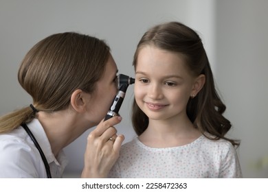 Focused attentive kids otolaryngologist examining girls ear for infection, using otoscope. Positive relaxed friendly child visiting doctor for healthcare medical checkup, examination - Powered by Shutterstock