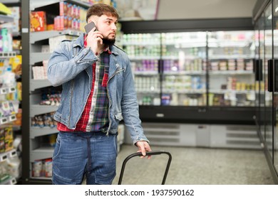 Focused Bearded Guy Talking On Phone During Shopping At Grocery Store