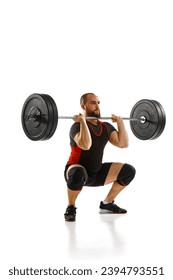 Focused bearded man, athlete with strong body training, lifting heavy weights, barbell against white background. Concept of sport, strength, gym, healthy lifestyle, power, endurance, weightlifting