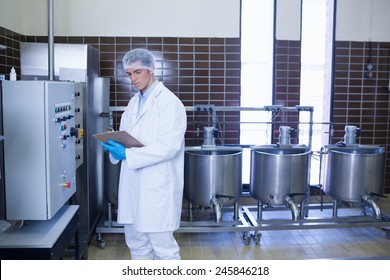 Focused biologist with safety gloves holding clipboard in the factory