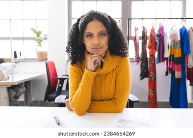 Focused biracial female fashion designer having video call at desk in studio. Fashion, design, creativity, clothing and small business, communication, technology, unaltered. - Powered by Shutterstock