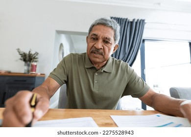 Focused biracial senior man analyzing bills on wooden table while sitting at home. Copy space, unaltered, lifestyle, home finance, budget and retirement concept. - Powered by Shutterstock