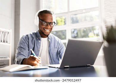 Focused Black Man Utilizing Digital Tools for Online Education in Home Office - Student, Marketer, or Journalist in Training. - Powered by Shutterstock