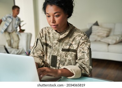 Fokussierter schwarzer Soldat mit Laptop am Tisch