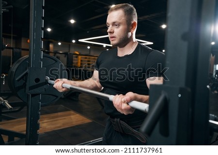 Focused bodybuilder preparing to do weight-lifting exercise