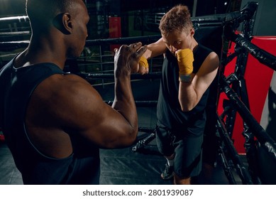 Focused boxer blocking punch during sparring drill with coach in ring. Concept of rivalry pressure, boxing discipline, resilience training, defense strategy and fitness promotion.