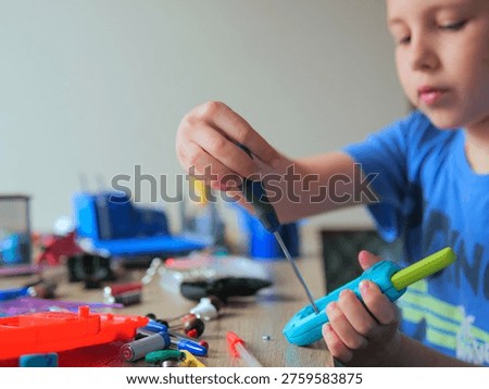 Focused Boy Using Screwdriver on Electronic Toy, Junior Technician Repairing Gadget at Desk, Hands-on STEM Education and Mechanical Skills for Kids