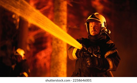 Focused Brave Professional Firefighter Using a Firehose to Fight a Raging Dangerous Forest Fire. Experienced Fireman Skillfully Manages a Stressful Situation and Stays Protected. - Shutterstock ID 2258646001