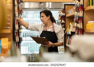 Focused brazilian businesswoman with clipboard checking product inventory inside grocery store. business, workplace, successful, entrepreneur, occupation concept. - Powered by Shutterstock