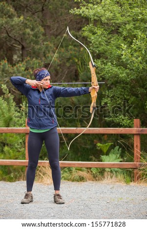 Focused brunette practicing archery at the range