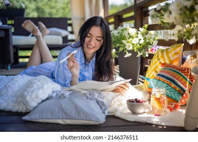 Focused brunette woman thinking imagination with pen and notepad at nature summer outdoor village terrace. Pensive Asian female taking notes writing paper diary relaxing on balcony countryside house