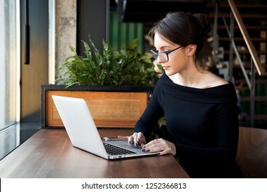 Focused business woman sit on cafe working on laptop, concentrated serious female working with computer and notebook in coffee shop, freelancer, studying online, browse internet, checking bills