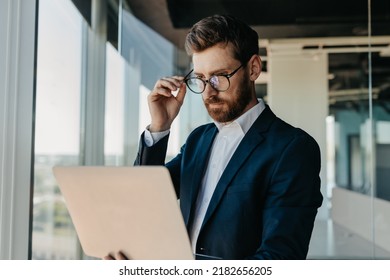 Focused Businessman Looking At Laptop Computer, Working In Modern Office Interior, Reading Emails From His Business Partners, Working On Marketing Research, Copy Space