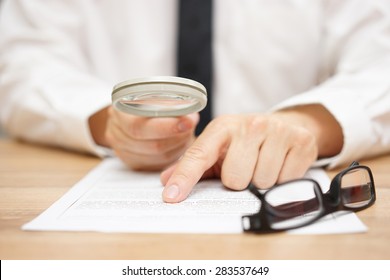 Focused businessman is reading through  magnifying glass document - Shutterstock ID 283537649