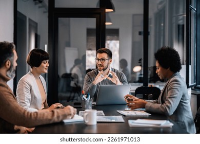 A focused businessman is sitting at the meeting room with colleagues and brainstorming about project. - Shutterstock ID 2261971013