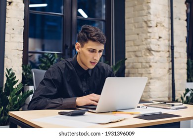 Focused Businessman Working On Laptop Computer At Table In Office