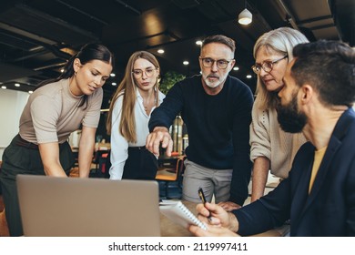 Focused businesspeople having a discussion while collaborating on a new project in an office. Group of diverse businesspeople using a laptop while working together in a modern workspace. - Shutterstock ID 2119997411