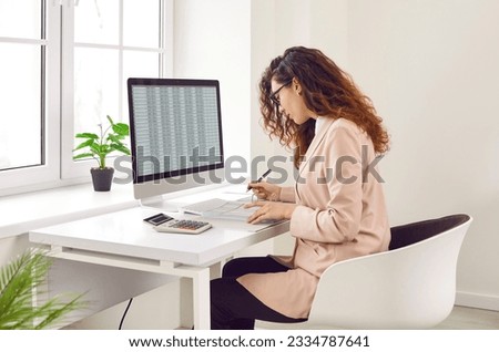 Focused businesswoman analyzing financial spreadsheet report on computer screen. Accountant, analyst, financial manager checking electronic spreadsheet and doing paperwork on office