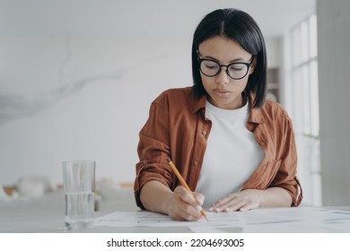 Focused Businesswoman In Glasses Works On Business Project, Makes Notes, Sitting At Workplace Desk. Modern Female Manager Freelancer Working, Writing Draft Plan, Solving Work Task In Home Office.