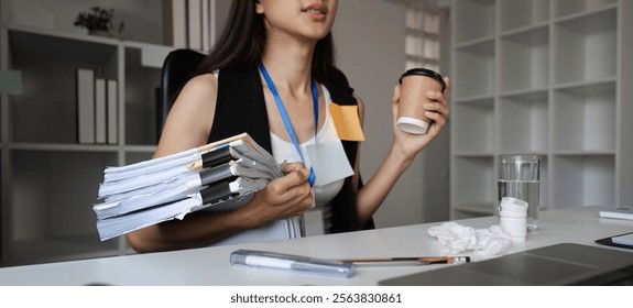 Focused Businesswoman Multitasking at Office Desk with Documents and Coffee in a Modern Workspace Environment - Powered by Shutterstock