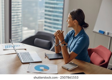 A focused businesswoman thoughtfully reflects in a modern office with stunning views of the city skyline - Powered by Shutterstock