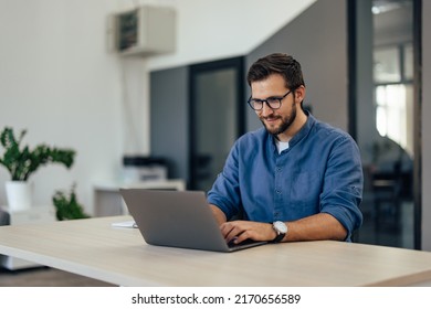 Focused busy male working online, over the laptop, at the office. - Powered by Shutterstock