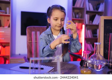 Focused Caucasian little girl doing chemistry experiment looking at test tube in evening at living room. Science, hobbies, learning, education, discovery, childhood and domestic life. - Powered by Shutterstock