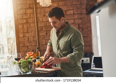 Focused Caucasian male cook cutting a bell pepper with a chefs knife in the kitchen - Powered by Shutterstock