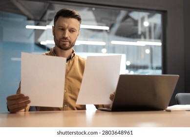 Focused Caucasian Man Analyzing Documents In Office, Business Concept