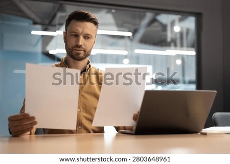 Focused Caucasian Man Analyzing Documents In Office, Business Concept