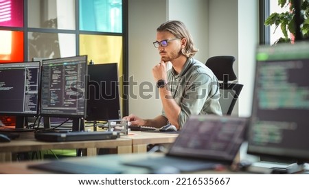 Focused Caucasian Man Coding On Desktop Computer in Stylish Office Space. Male Software Engineer Developing Innovative Application For Business Customers in Technological Start-up Company.