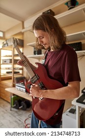 Focused caucasian man playing electric guitar at home. Concept of domestic hobby, entertainment and leisure. Professional male rock musician and songwriter. Modern spacious apartment at daytime