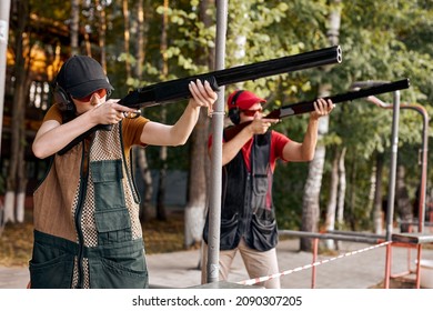 Focused caucasian skilled people in goggles and headset on tactical gun training classes, aiming rifle at target. Shooting and Weapons. Outdoor Shooting Range At Summer Evening. Side View.