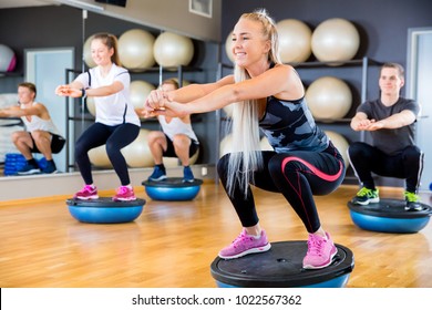 Focused And Cheerful Group Training Squats On Half Ball At Fitness Gym