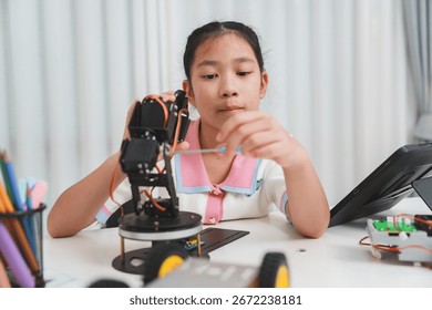 Focused child assembling a robotic arm. Hands-on learning and technology.