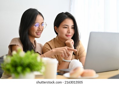 Focused And Concentrated Two Asian Female College Student Doing Work Assignment Together, Researching Some Information On The Internet Via Laptop Computer.