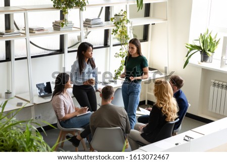 Focused concerned diverse office employees gather together in modern light co-working space deliberating, discussing risks, solve business common problems, teamwork and partnership, brainstorm concept