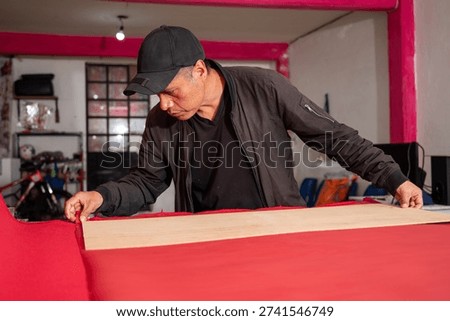 Focused Craftsman Aligning Red Polyester for Accurate Cut