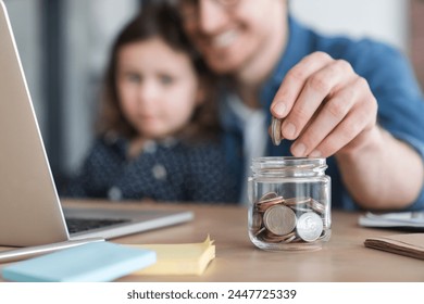 Focused cropped shot of a little girl daughter and her young father putting money to the moneybox piggy bank. Personal Savings. For future, mortgage loan savings home in crisis coronavirus concept. - Powered by Shutterstock