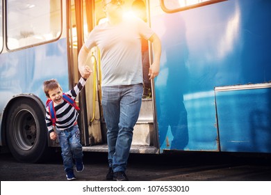 Focused Dad Is Holding His Little Sons Hand Tightly Making Sure He Doesn't Run Off Playfully While Leaving The Bus.