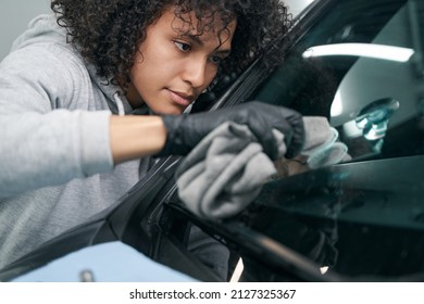 Focused detailer cleaning car glass with microfiber towel - Powered by Shutterstock