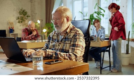Focused elderly man of professionals engaged in discussing reports, reviewing charts, and making data-based decisions. Concept of business, modern office environment, generations together. Ad