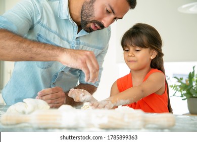 Focused Father Teaching His Girl To Bake Bread Or Pies. Focused Dad And Daughter Kneading Dough On Kitchen Table With Flour Messy. Family Cooking Concept