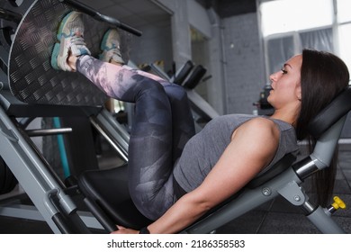 Focused Female Athlete Working Out On Leg Press Machine